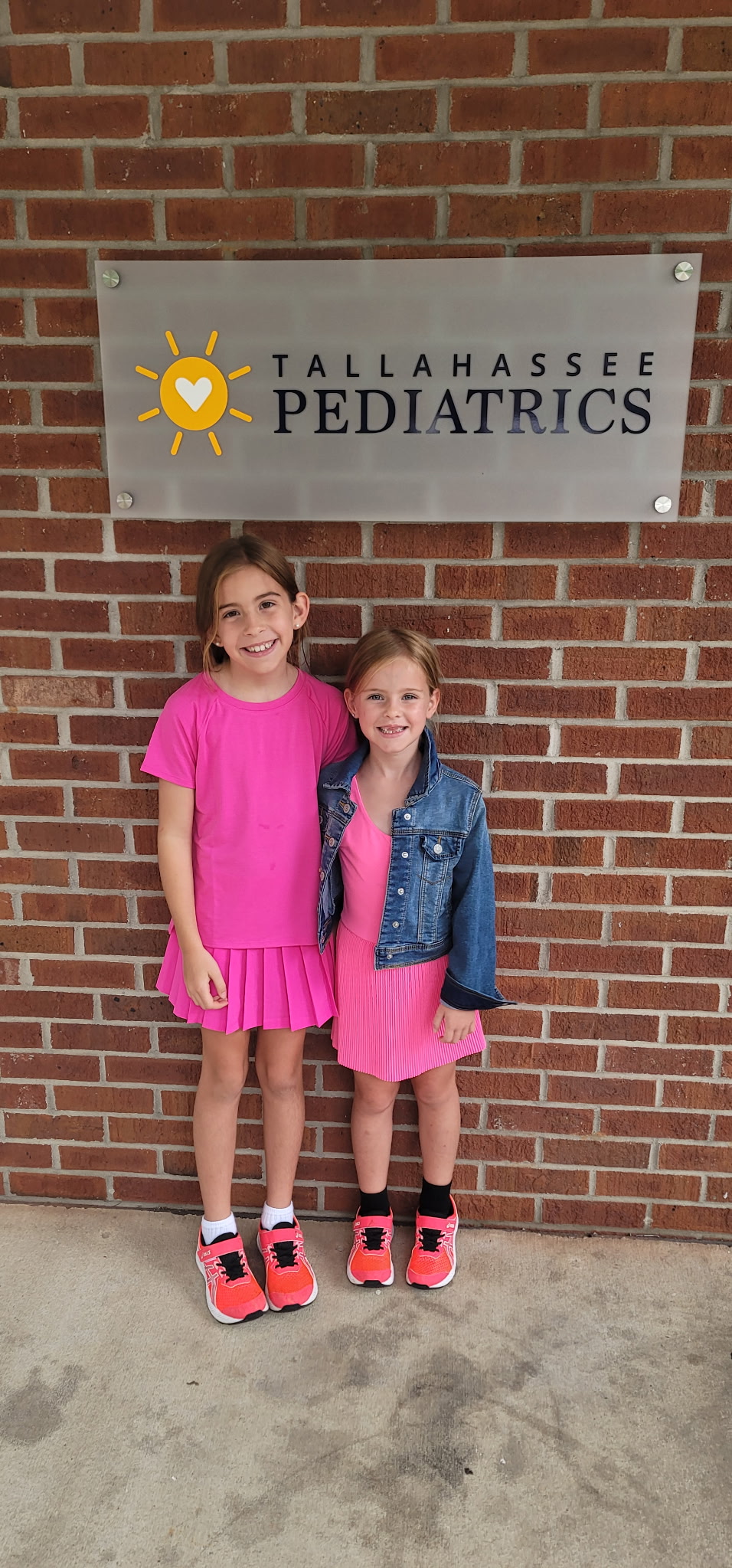Sisters pose below Tallahassee Pediatrics entry sign